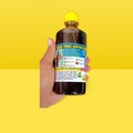 Hakki Pikki Adivasi hair oil for hair growth bottle held in hand with yellow cap and label