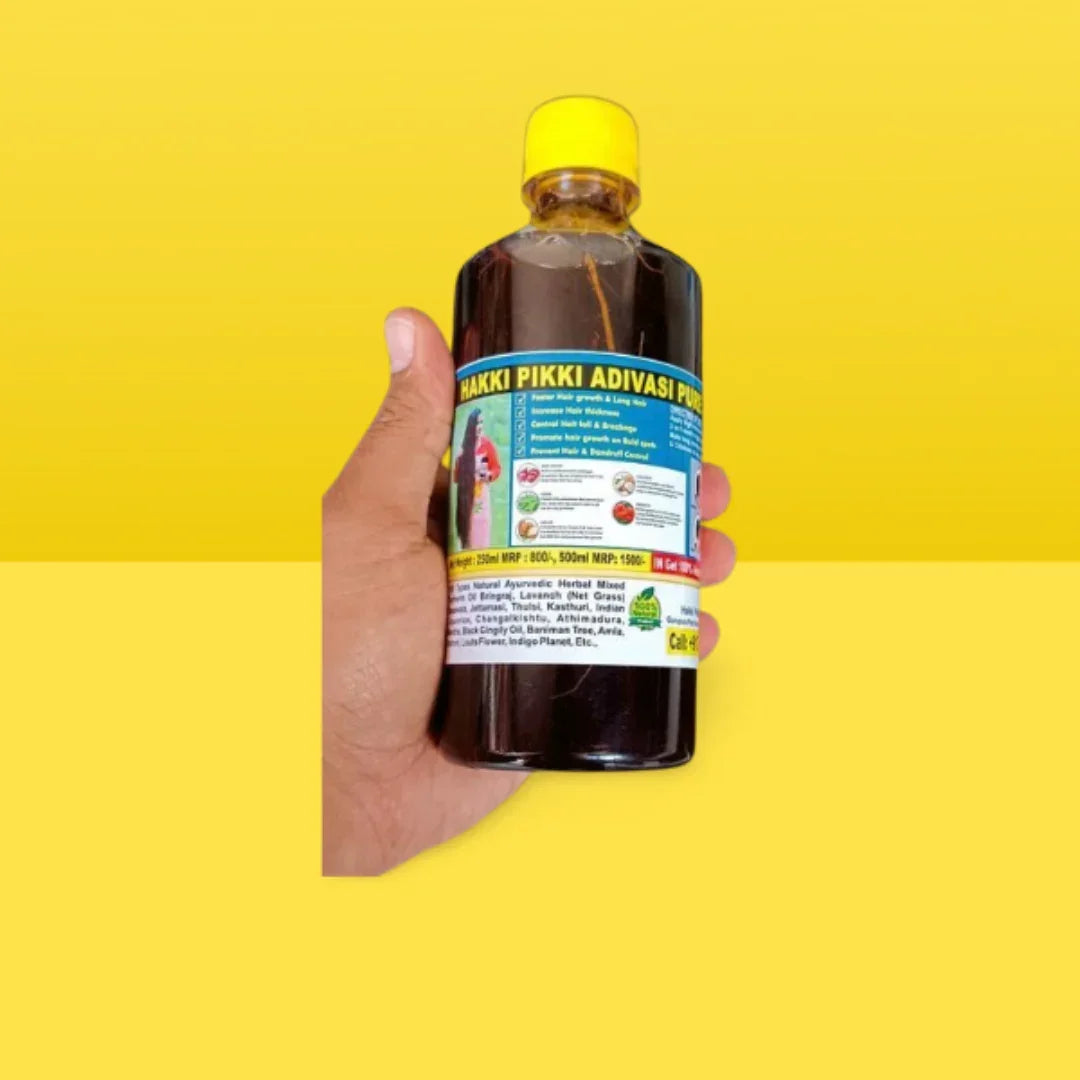 Hakki Pikki Adivasi hair oil for hair growth bottle held in hand with yellow cap and label