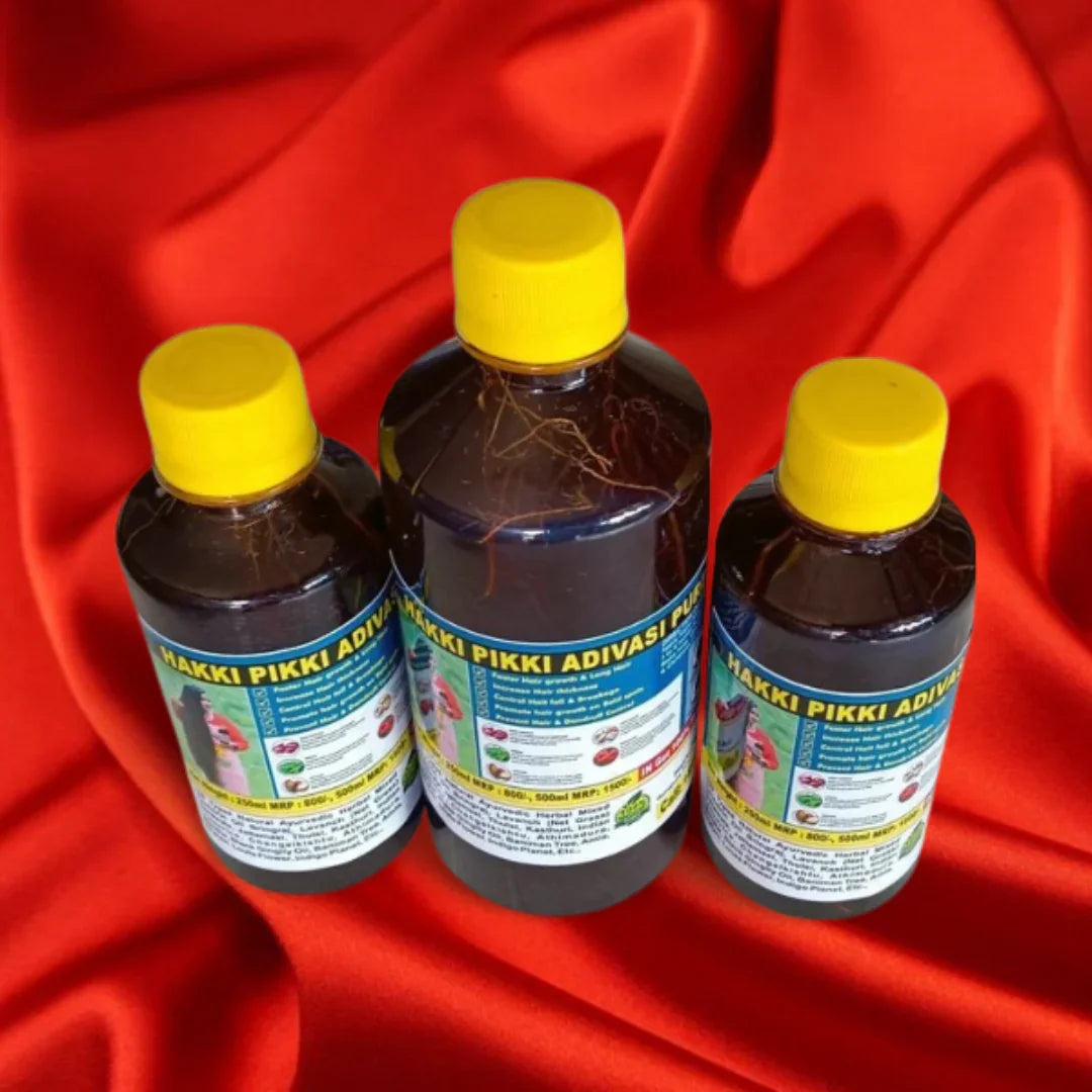 Three bottles of Hakki Pikki Adivasi hair oil for hair growth with yellow caps on red fabric
