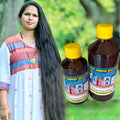 Hakki Pikki Hair Oil bottles next to a woman with long, healthy black hair outdoors
